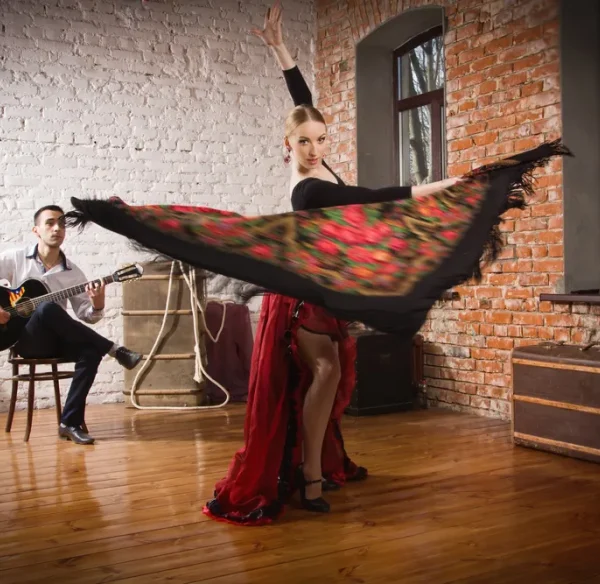 Una chica bilando flamenco mientras un hombre toca la guitarra